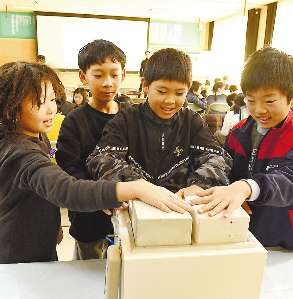 断熱性能の異なる建築材に触れる子どもたち。「こっちは温かいよ」「こっちは全然熱を通さないね」