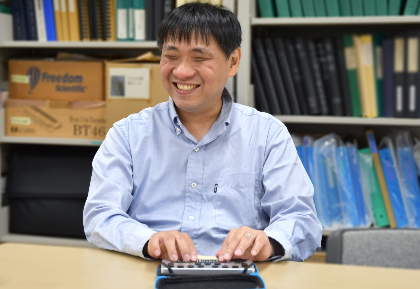 点字携帯端末を操作している大河内直之さんの写真
